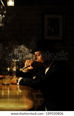 Portrait of a man smoking cigar by the bar. Mafia, retro or gangster style.