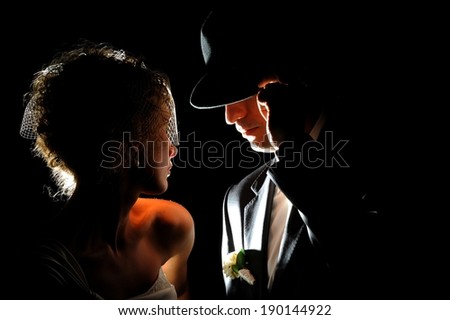 Silhouettes of a beautiful wedding couple in the dark background. Retro or vintage style.