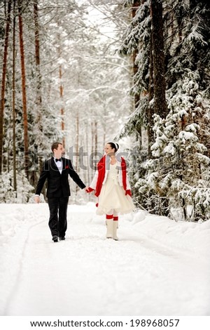 Couple walking in winter forest happy and joyful holding hands on romantic date in winter snow forest landscape.