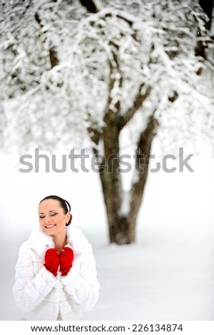 Beautiful woman with red gloves in winter fur coat. Winter landscape.