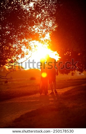 Love couple walking and kissing in the sunset. Sun flare photo.