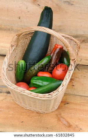Composition with basket and vegetables on a wooden background