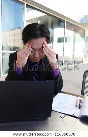 A chinese asian business man expressing stress on computer