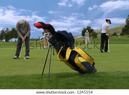 A photo of a golf club bag with golfers in the background (Focus on Golf Bag)