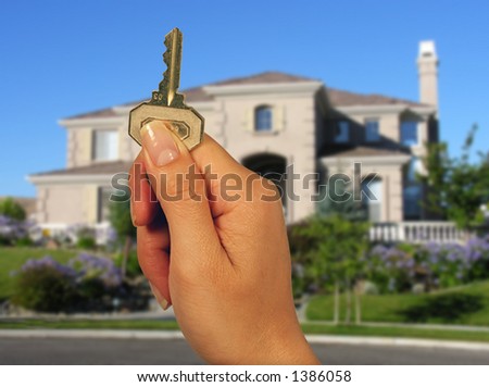A woman holding a house key with a new home in the background