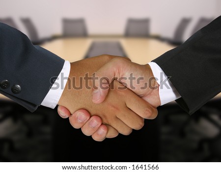 Two businessmen shaking hands in the boardroom