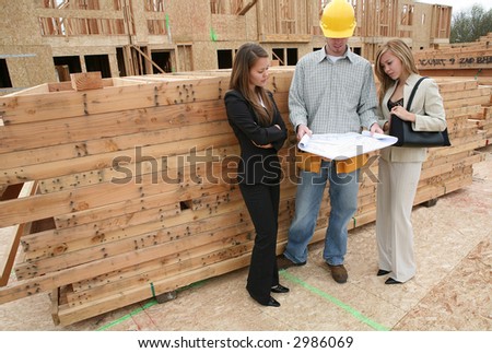 Two real estate agents and a home builder discussing the blueprint