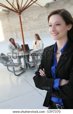 A pretty, young business woman smiling with co-workers in background