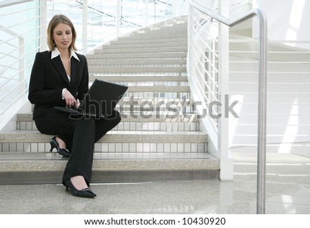 A beautiful blonde business woman on stairs on computer