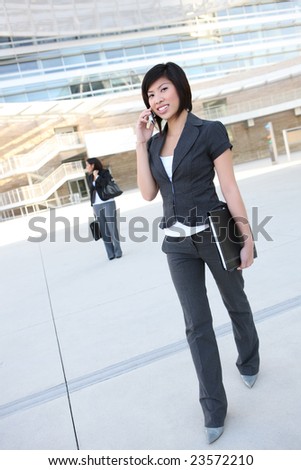 A pretty asian business woman walking to the office on phone