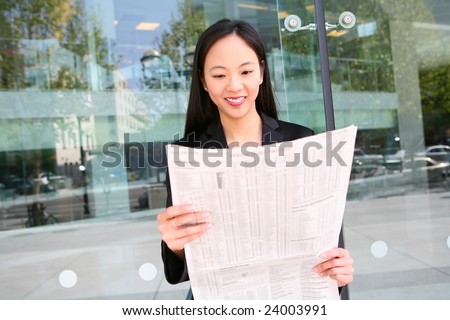 A pretty asian business woman reading the newspaper