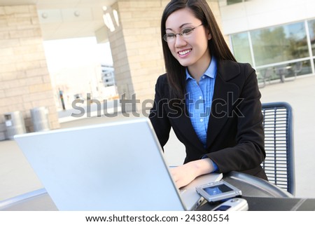 A young, pretty asian business woman at office building on laptop computer