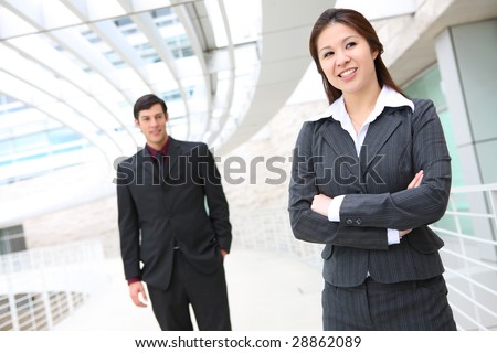 A pretty asian business woman at work with co-worker in background
