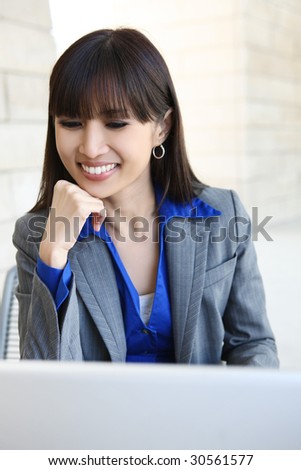A young, pretty asian business woman at office building with laptop computer