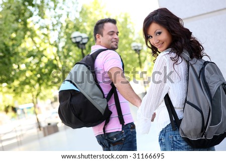 Attractive man and woman couple students walking to class at college