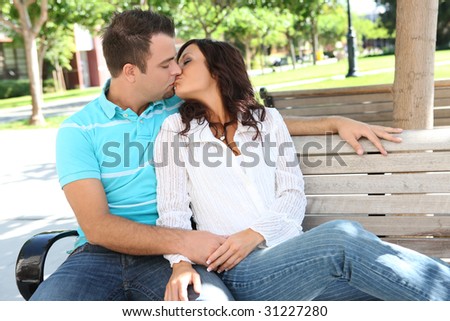 Attractive Couple kissing on a bench at college campus
