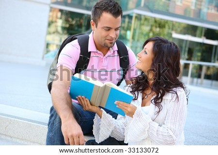 A man and woman student at school studying outside library
