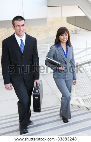 An attractive, diverse business man and woman team on stairs at office building