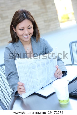 A pretty asian business woman at office reading newspaper