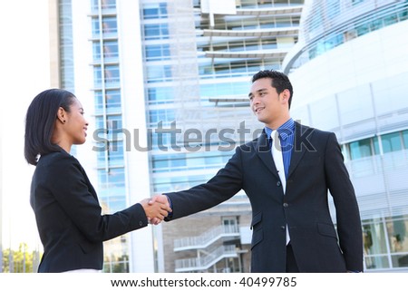 Attractive man and woman business team shaking hands at office building