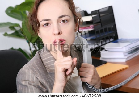 A business woman signaling silence while on the phone