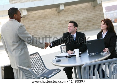 An attractive, diverse business man and woman team shaking hands at office building