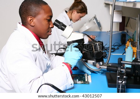 A handsome african man technician in the lab looking through microscope