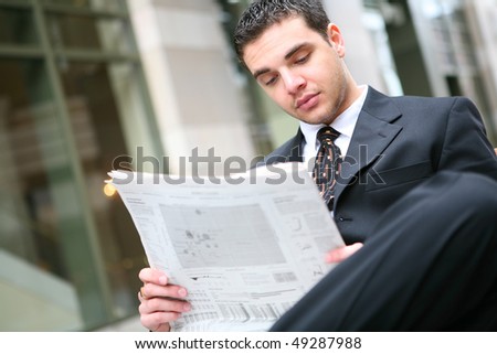 A handsome young business man reading the newspaper at office building