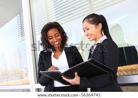 Two interracial (african and asian) business women team at office building
