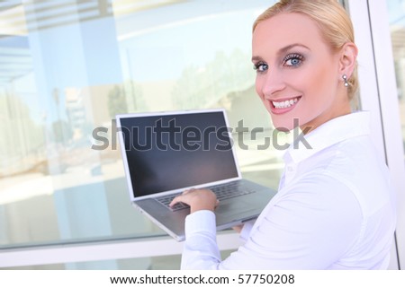 A pretty young blonde business woman on laptop computer at office