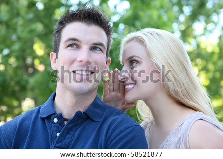 A man and woman couple in the park telling secrets (Focus on Woman)