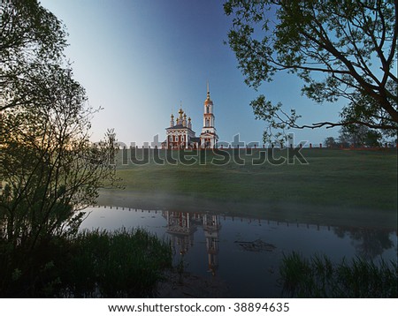 Church on the hill and its reflection in foggy river