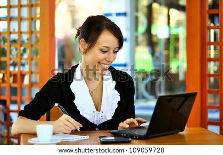 Woman using laptop and writing in notebook