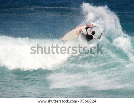Young man on surfboard kicking out of a wave