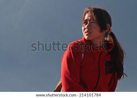 BALI, INDONESIA, AUGUST 14, 2014 : A young woman leads tourists to  the top of Batur Volcano in the light of dawn. Tourism is now the largest single industry in terms of income in Bali island.