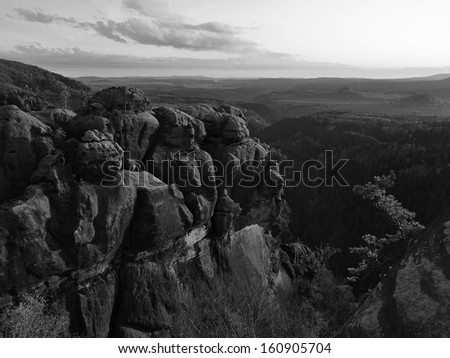 Autumn evening panorama view over sandstone rocks to fall valley of Saxony Switzerland. Sandstone peaks and hills increased from background. Black and white photo.