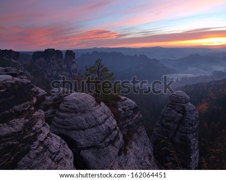 Autumn early morning view over sandstone rocks to fall valley of Saxony Switzerland. Sandstone peaks and hills increased from colorful background.