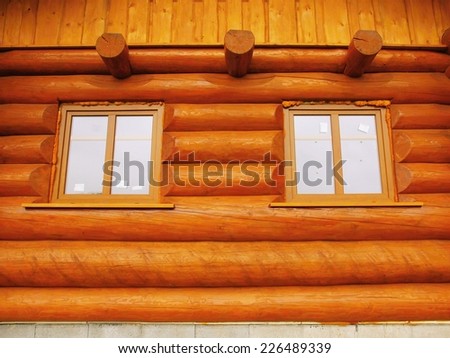 Detail of window built in wooden beams cabin wall. Painted wood with fungicide light red paint.