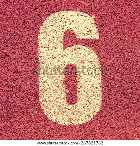 Number six. White track number on red rubber racetrack, texture of running racetracks in small stadium