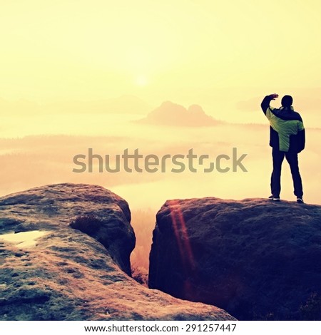Moment of loneliness. Man on the rock empires  and watch over the misty and foggy morning valley.