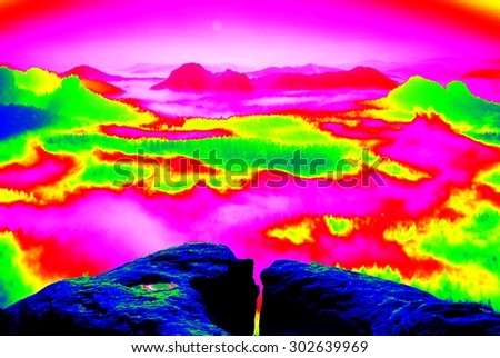 Colorful infrared photo of rocks above colorful fog in valley Amazing thermography colors.