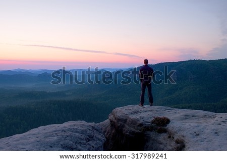 Hiker stand on the sharp corner of sandstone rock in rock empires park and watching over the misty and foggy morning valley to Sun