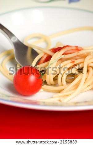 Closeup of a spaghetti-pasta dish with a fresh tomato and tomato sauce and fork