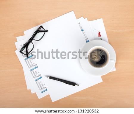 Blank paper with pen, glasses and coffee cup over financial documents