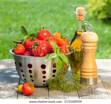 Fresh ripe tomatoes, olive oil bottle, pepper shaker and herbs on wooden table