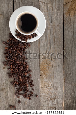 Coffee cup and beans on wooden table background with copy space