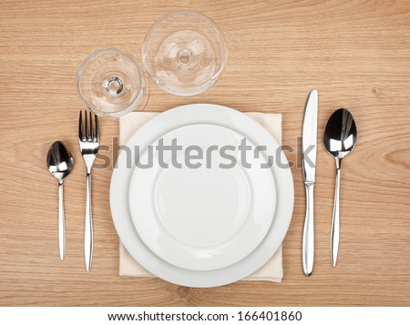 Empty plate, glasses and silverware set on wooden table