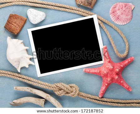 Travel photo frame on blue wooden texture with seashells and rope around