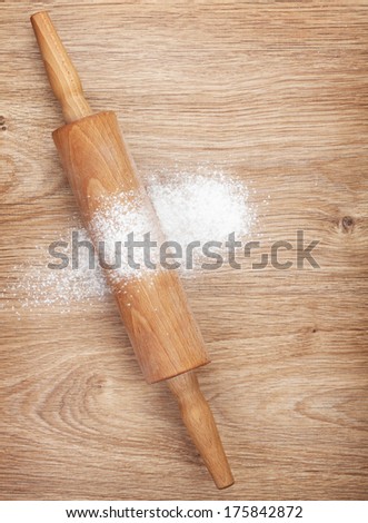 Rolling pin with flour on wooden table. View from above