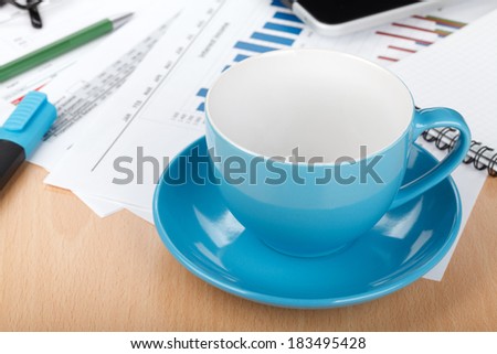 Empty cup on contemporary workplace with financial papers and office supplies